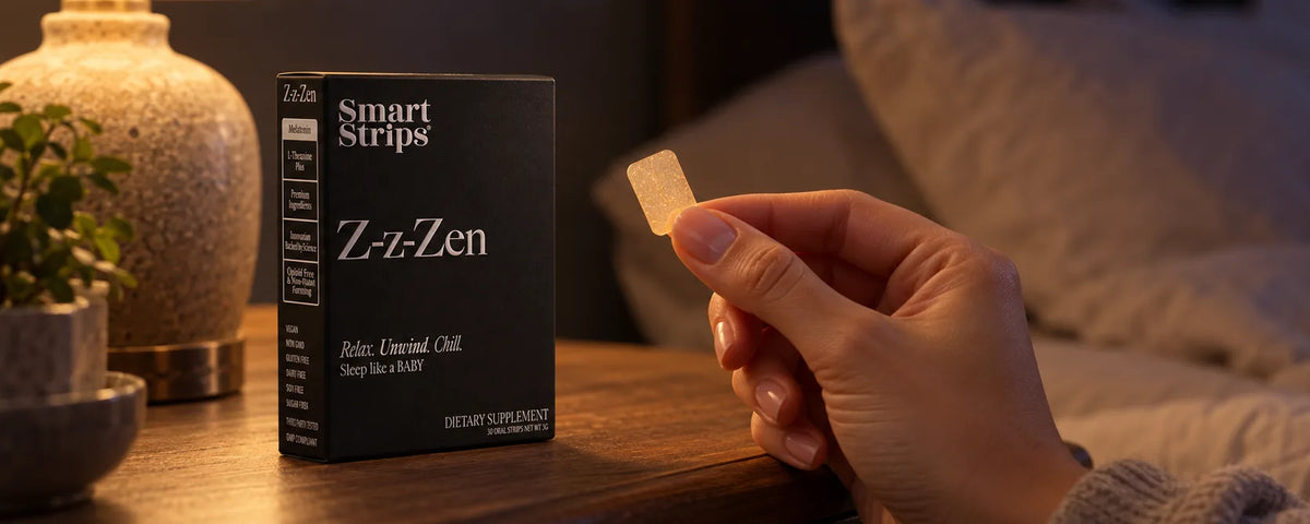 Hand holding a single oral dissolvable strip beside a Smart Strips Z-z-Zen box on a lamp-lit bedside table